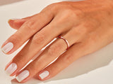 Rose gold band ring on a hand with manicured nails