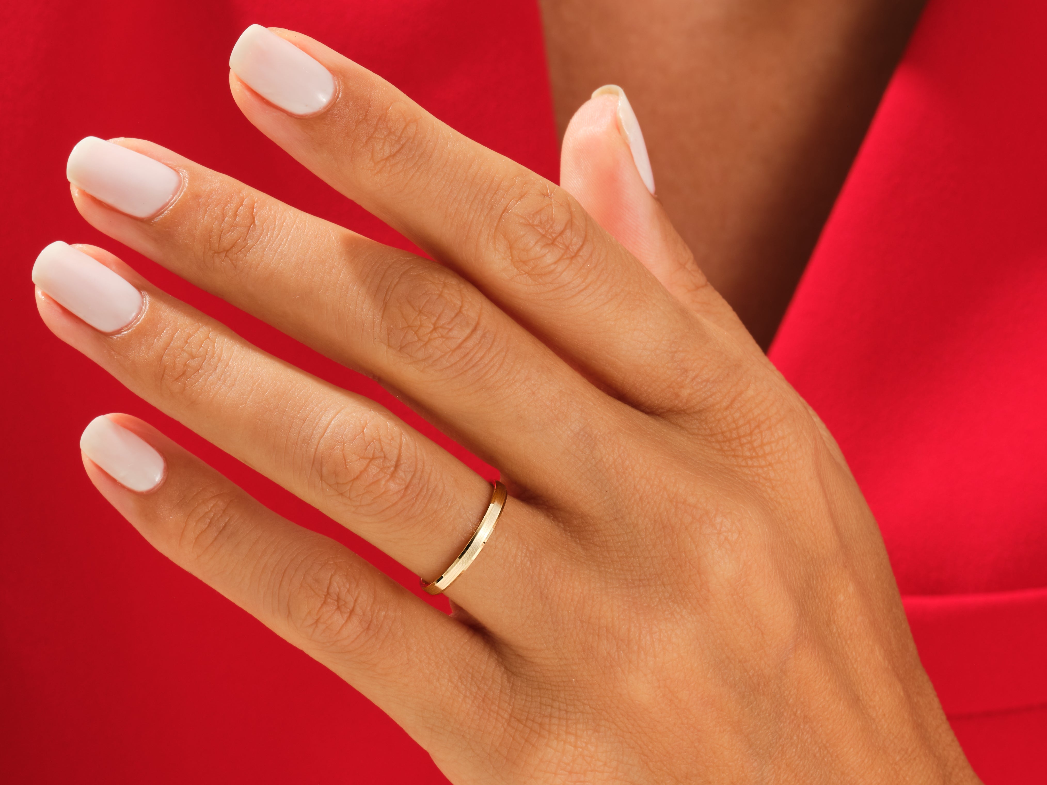 Gold wedding band on a hand with white nails, jewelry