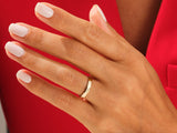 Gold wedding band on a hand with white nails, jewelry