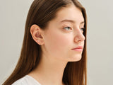 Gold triangle earrings on a woman's ear, jewelry product photography