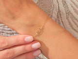 Gold daisy charm bracelet on a woman's wrist