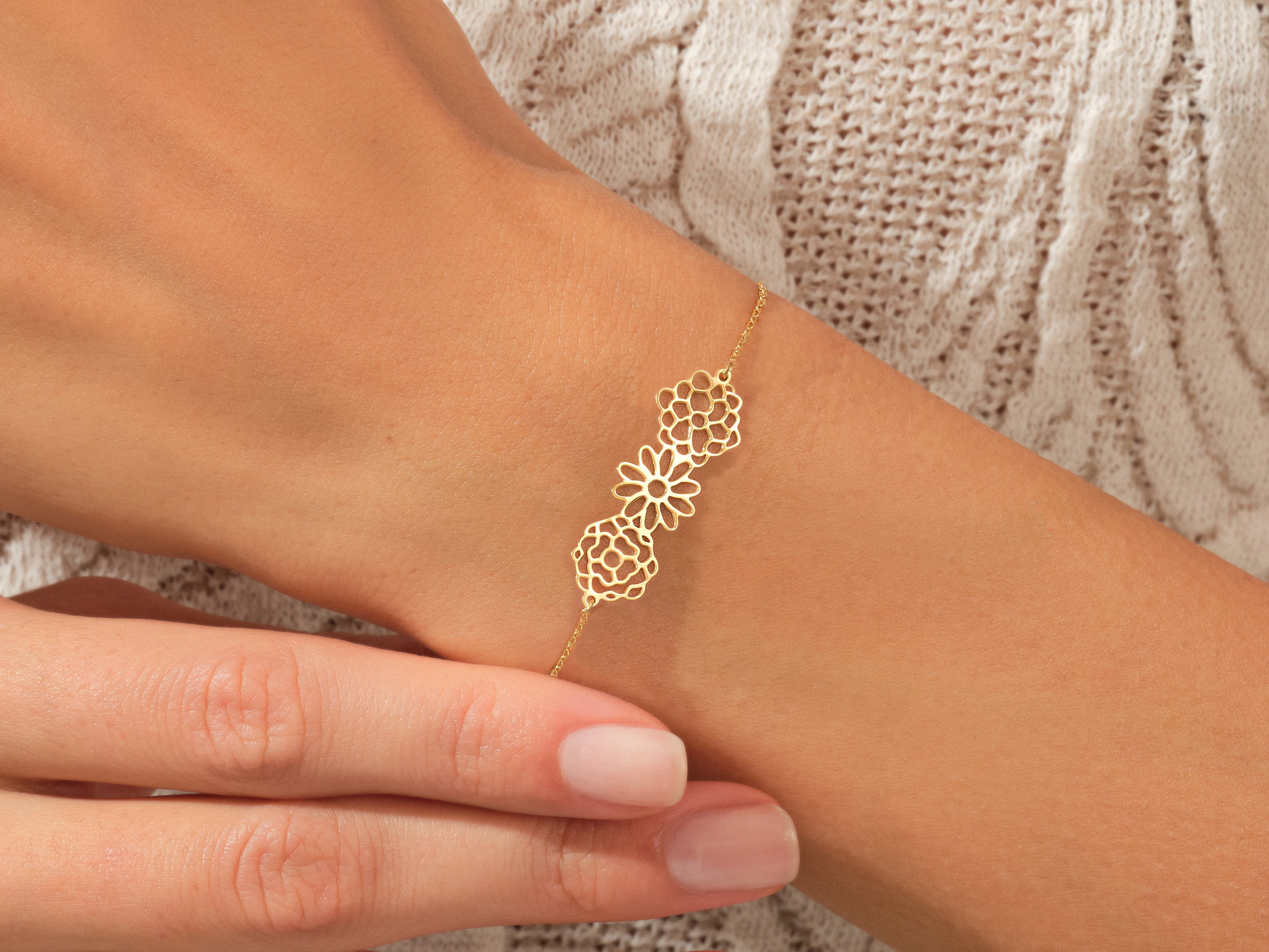 Gold floral bracelet on a woman's wrist