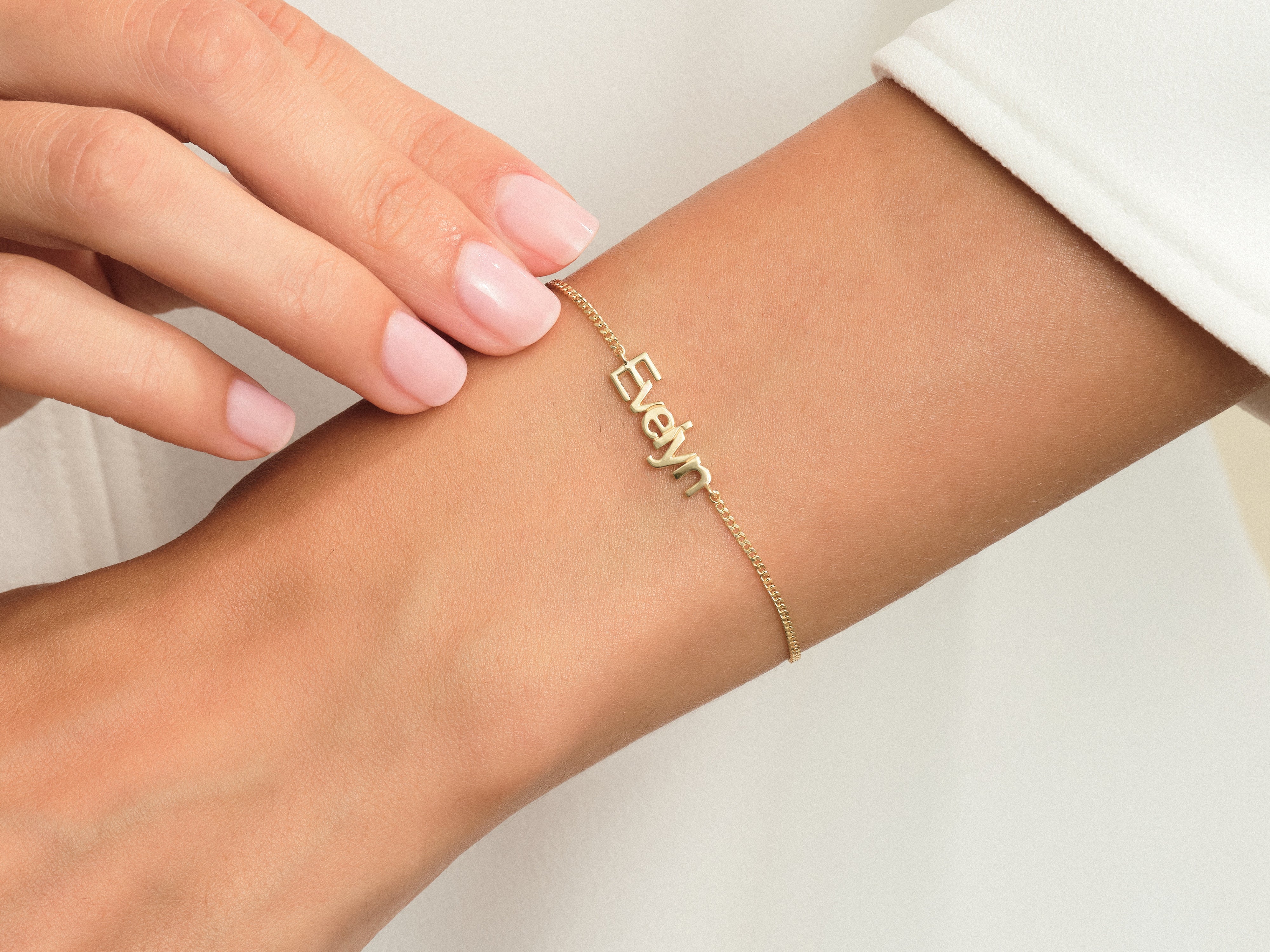 Gold Evelyn name bracelet on a woman's wrist