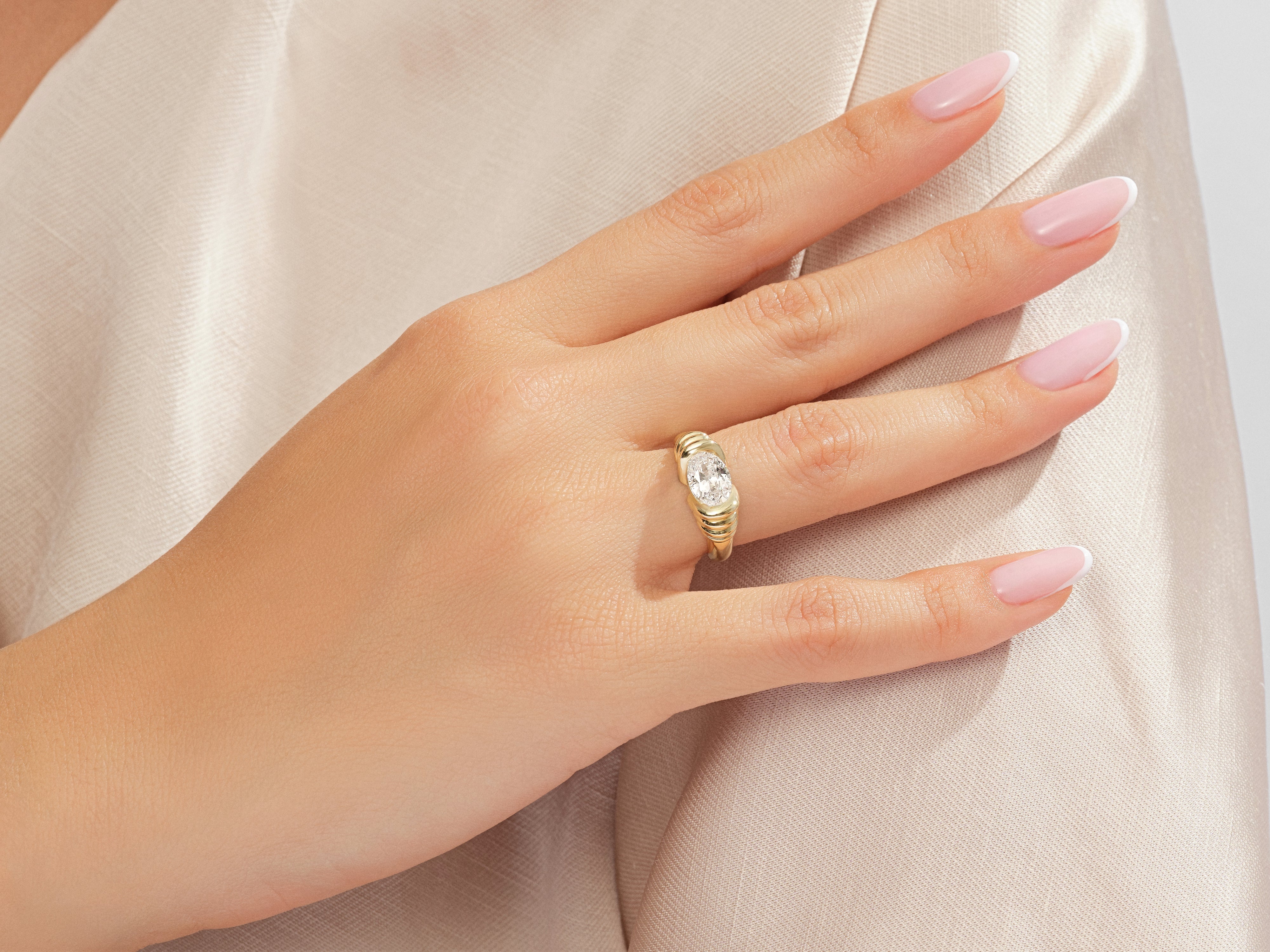 Gold oval diamond ring on a woman's finger, jewelry