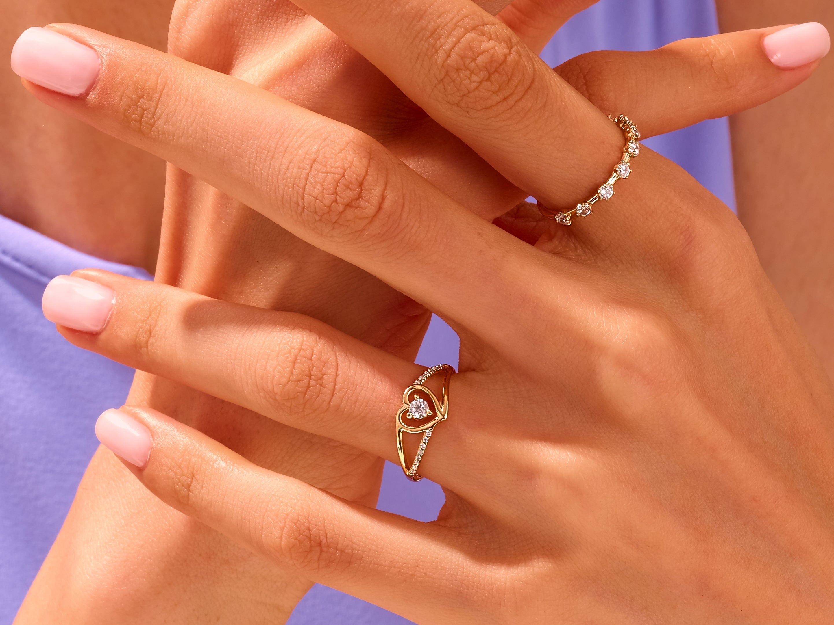 Gold heart and diamond rings on manicured hands