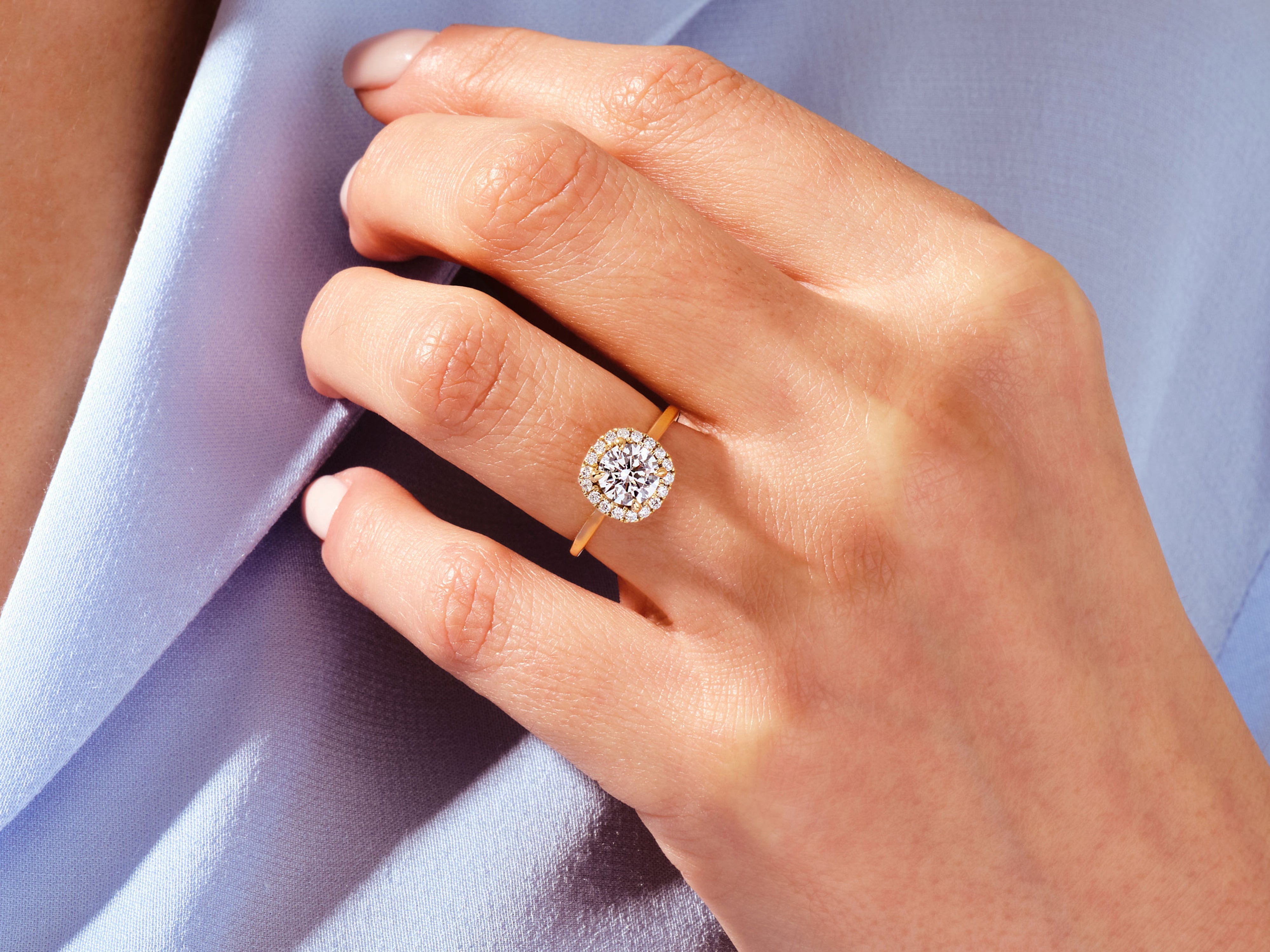 Gold diamond halo ring on a woman's hand