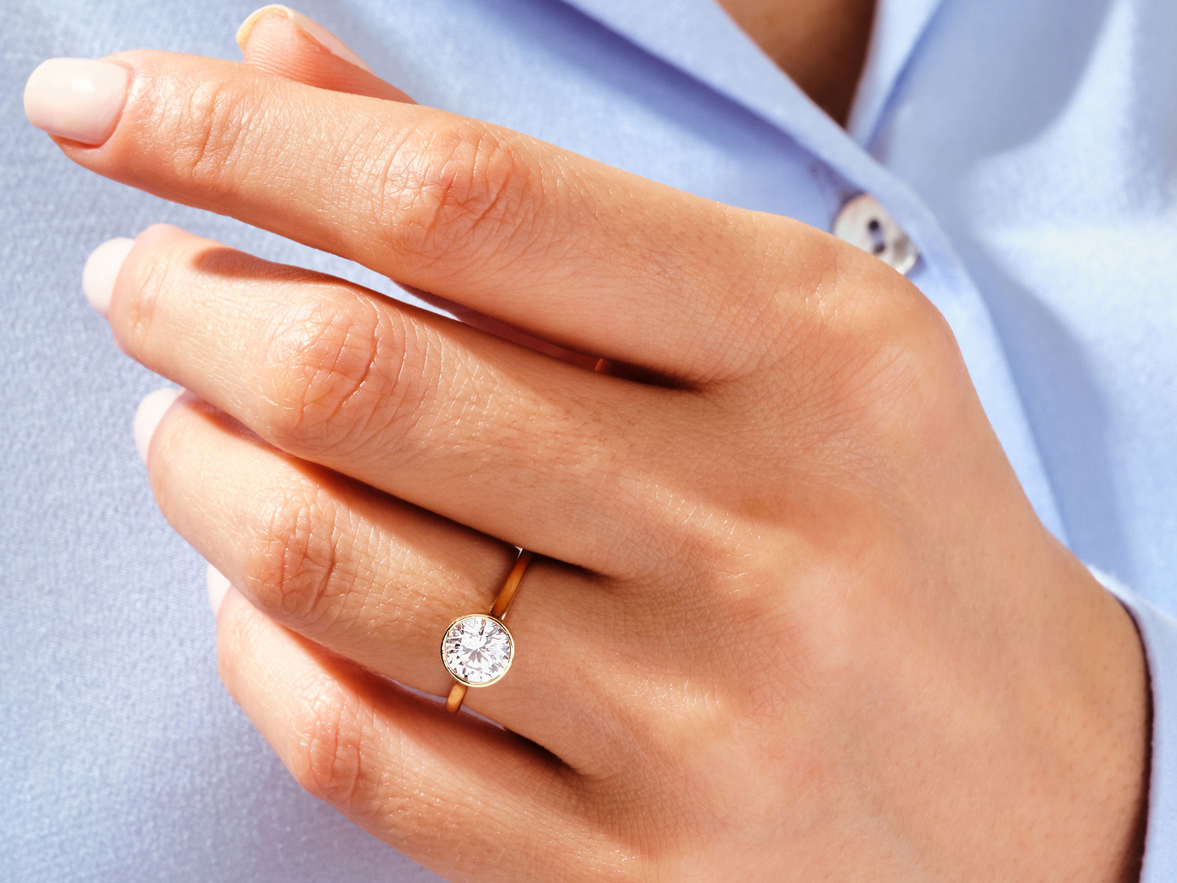 Gold bezel set diamond ring on hand, jewelry product photography