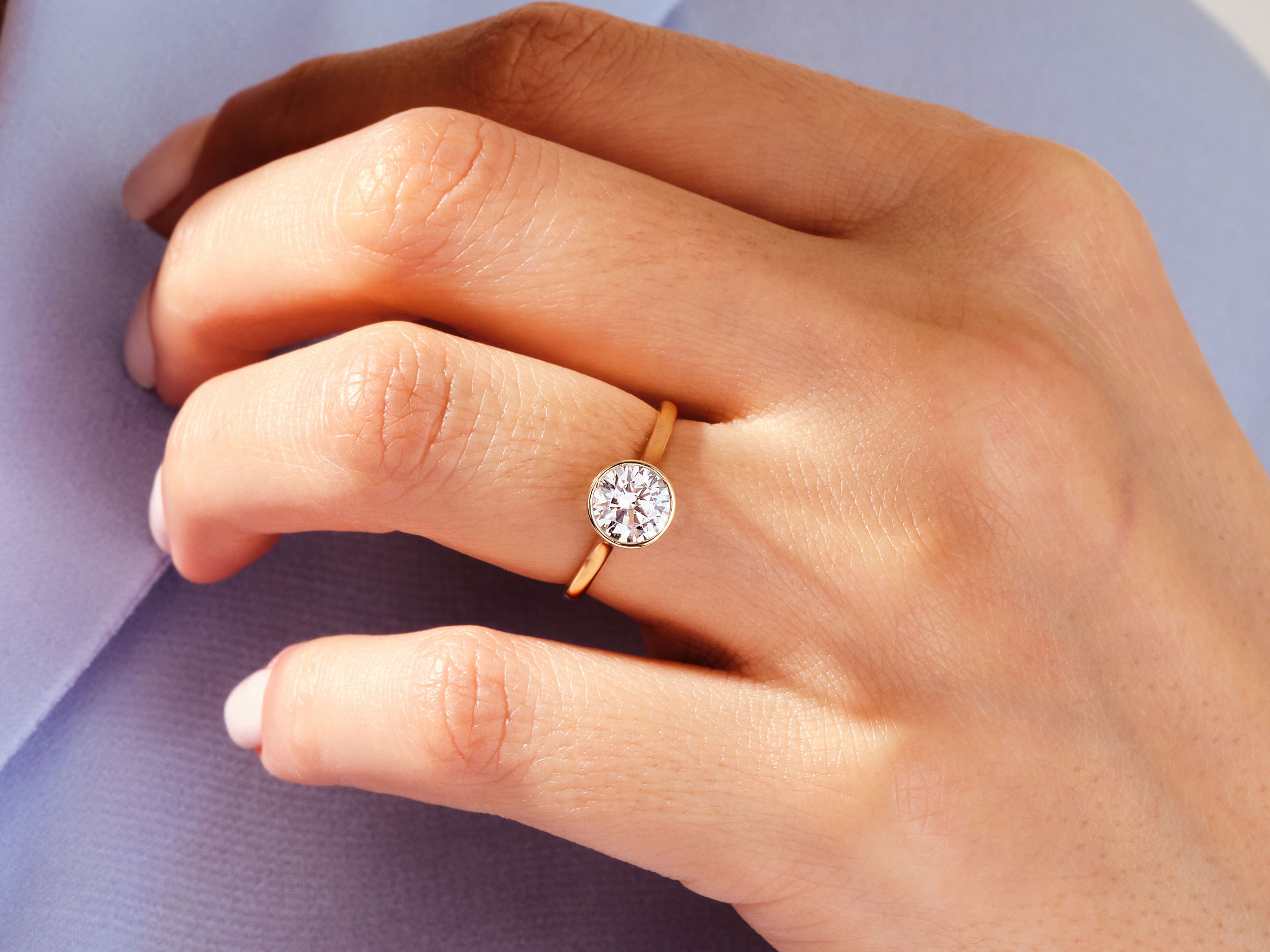 Gold bezel set diamond ring on a hand
