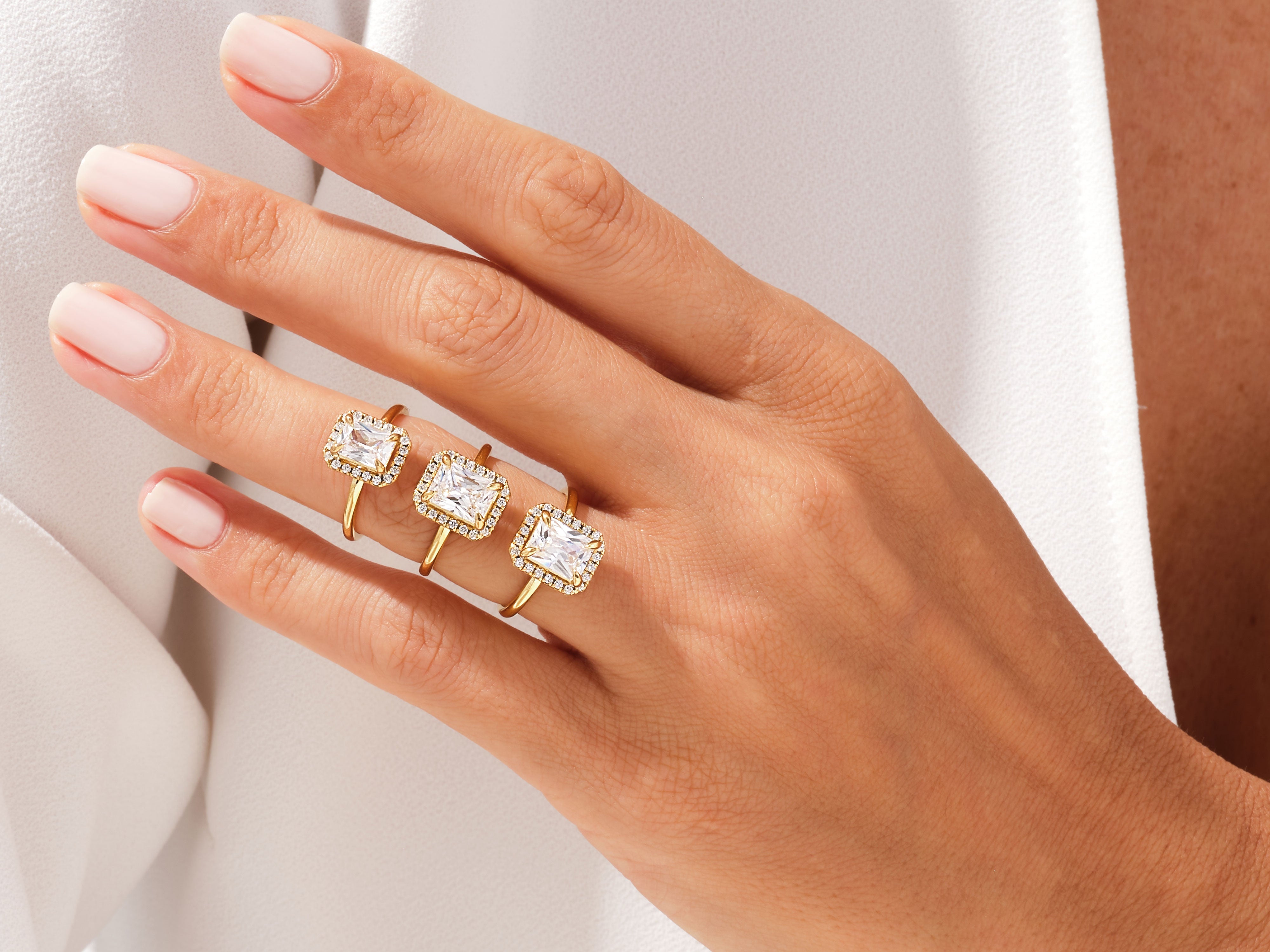 Three gold rings with square diamonds on a hand