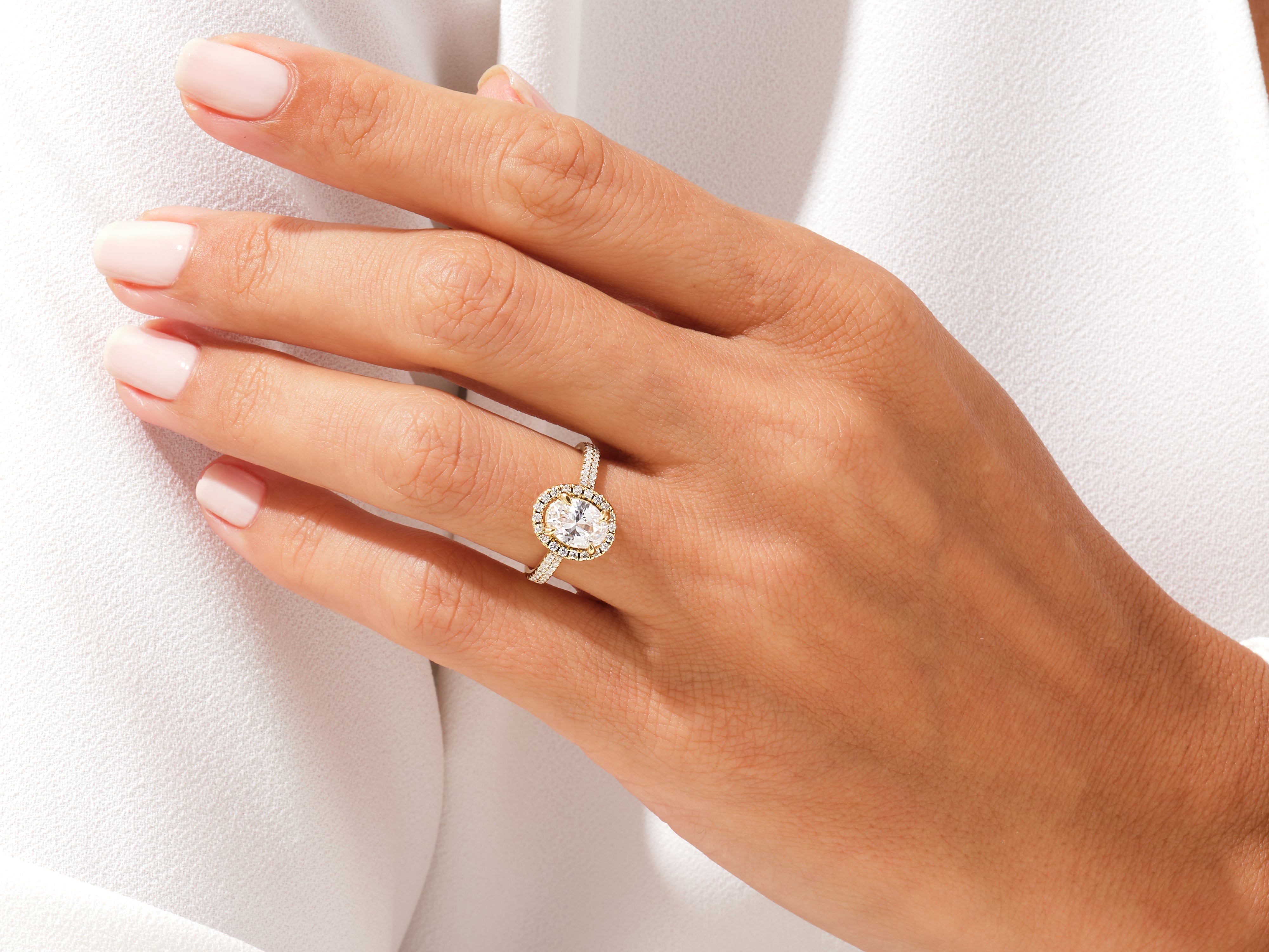 Oval diamond halo engagement ring in yellow gold