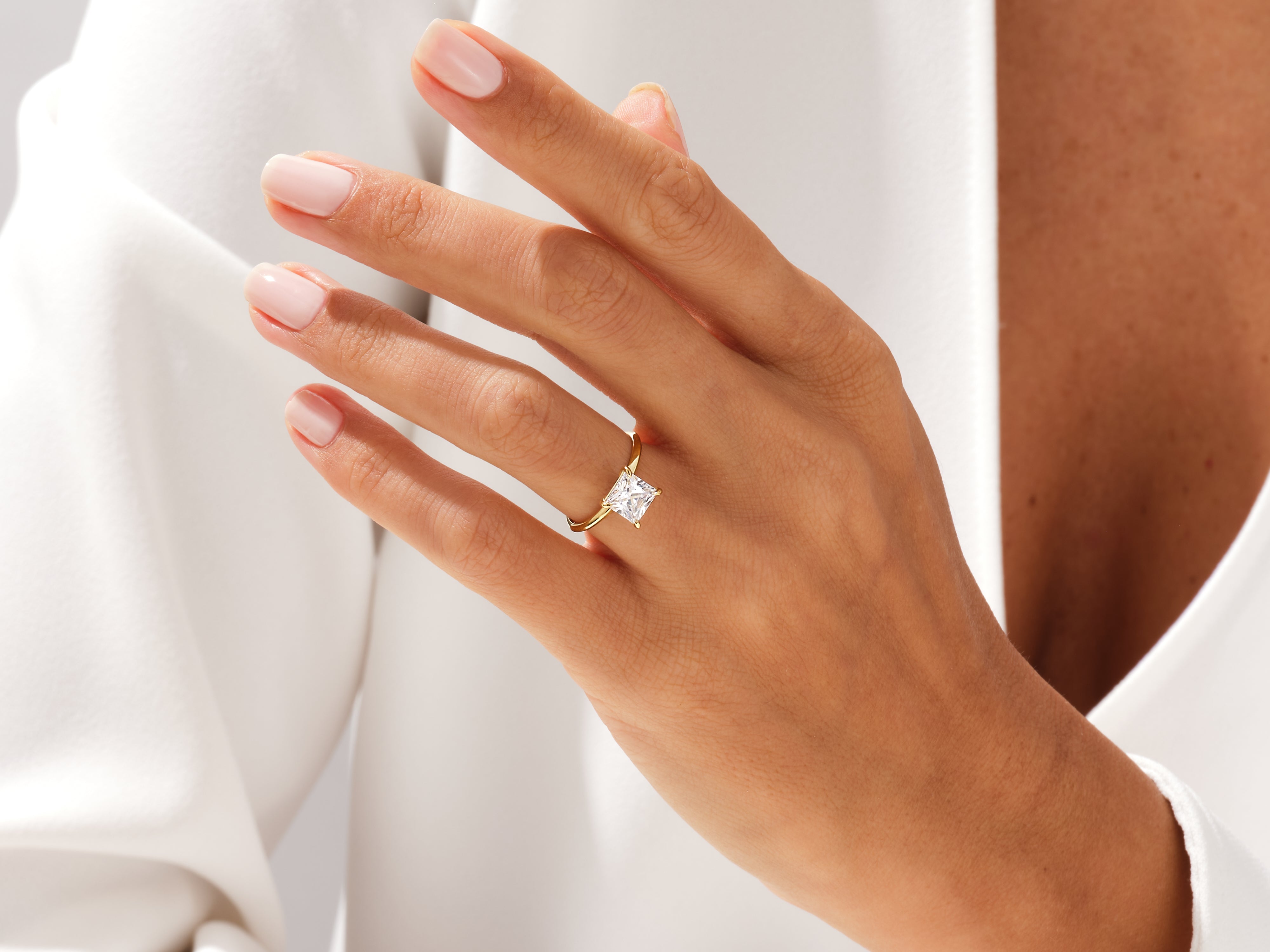 Gold princess cut diamond engagement ring on a woman's hand