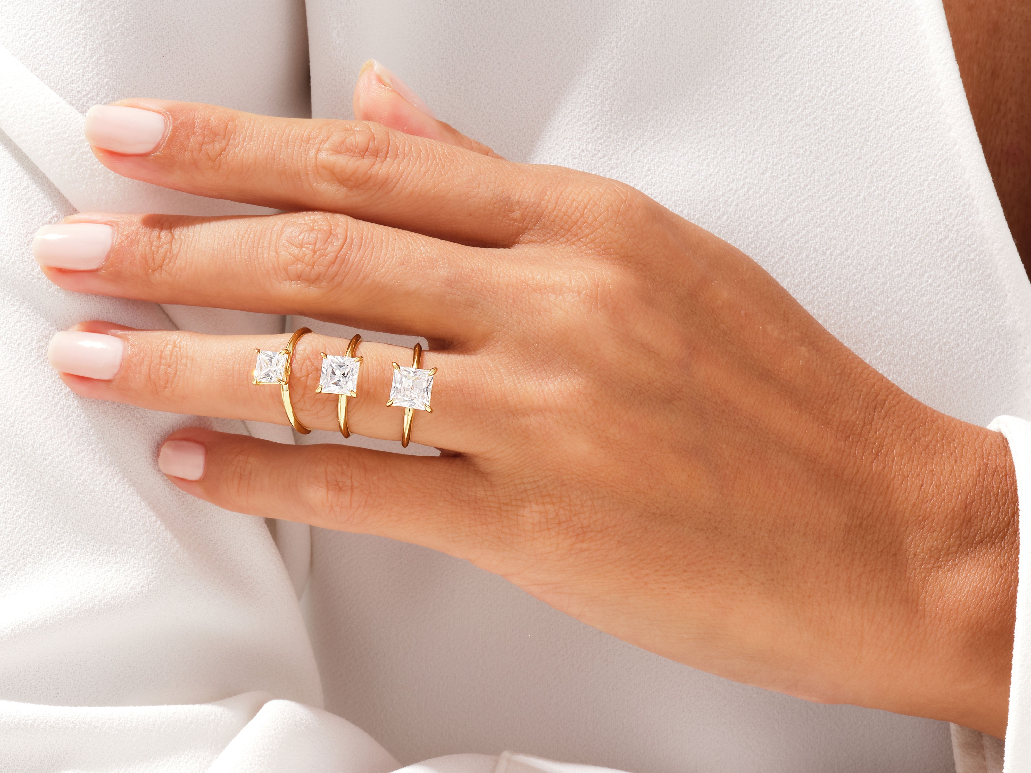 Gold rings with princess cut diamonds on a hand