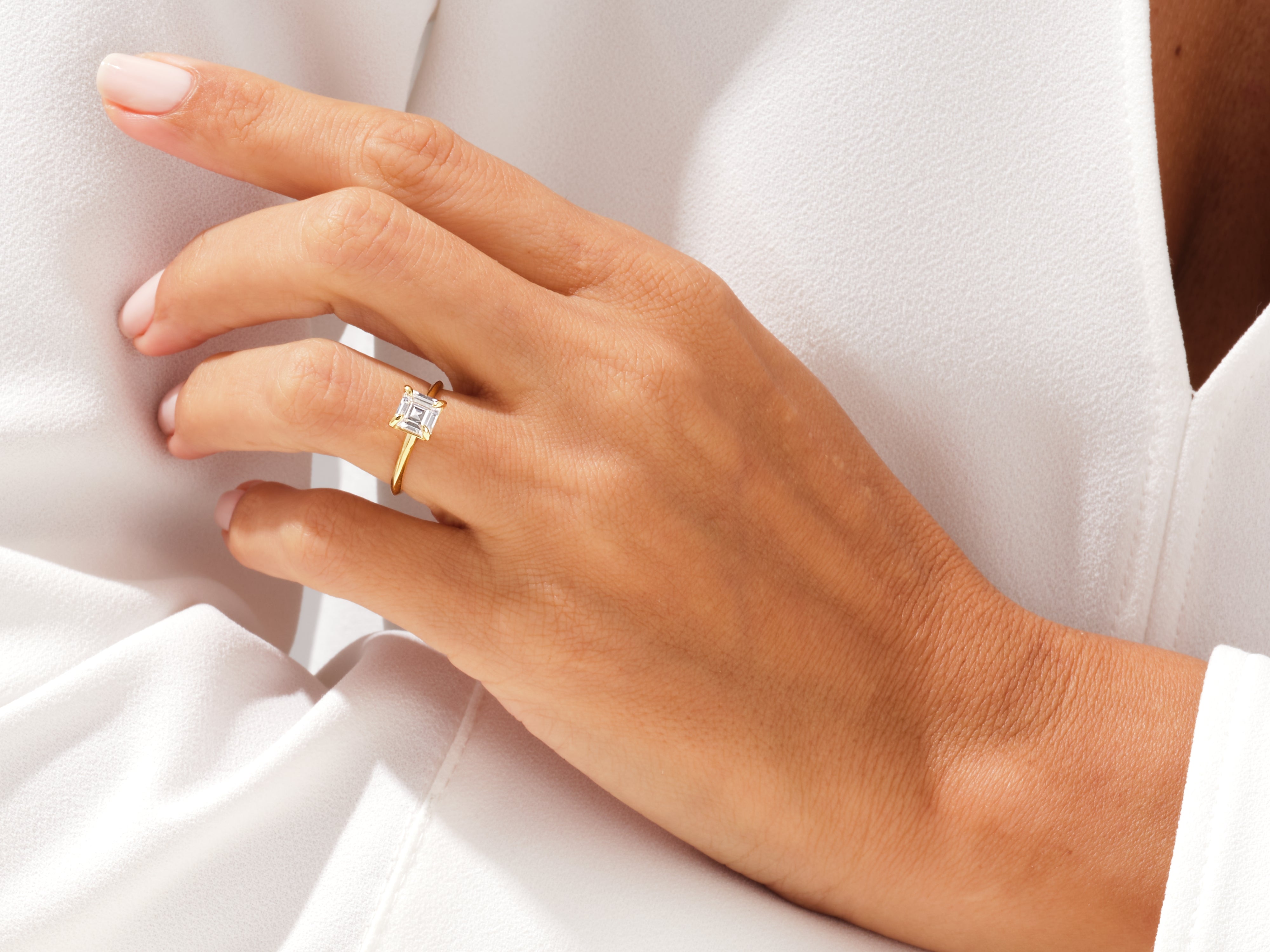 Gold ring with emerald cut diamond on a woman's hand