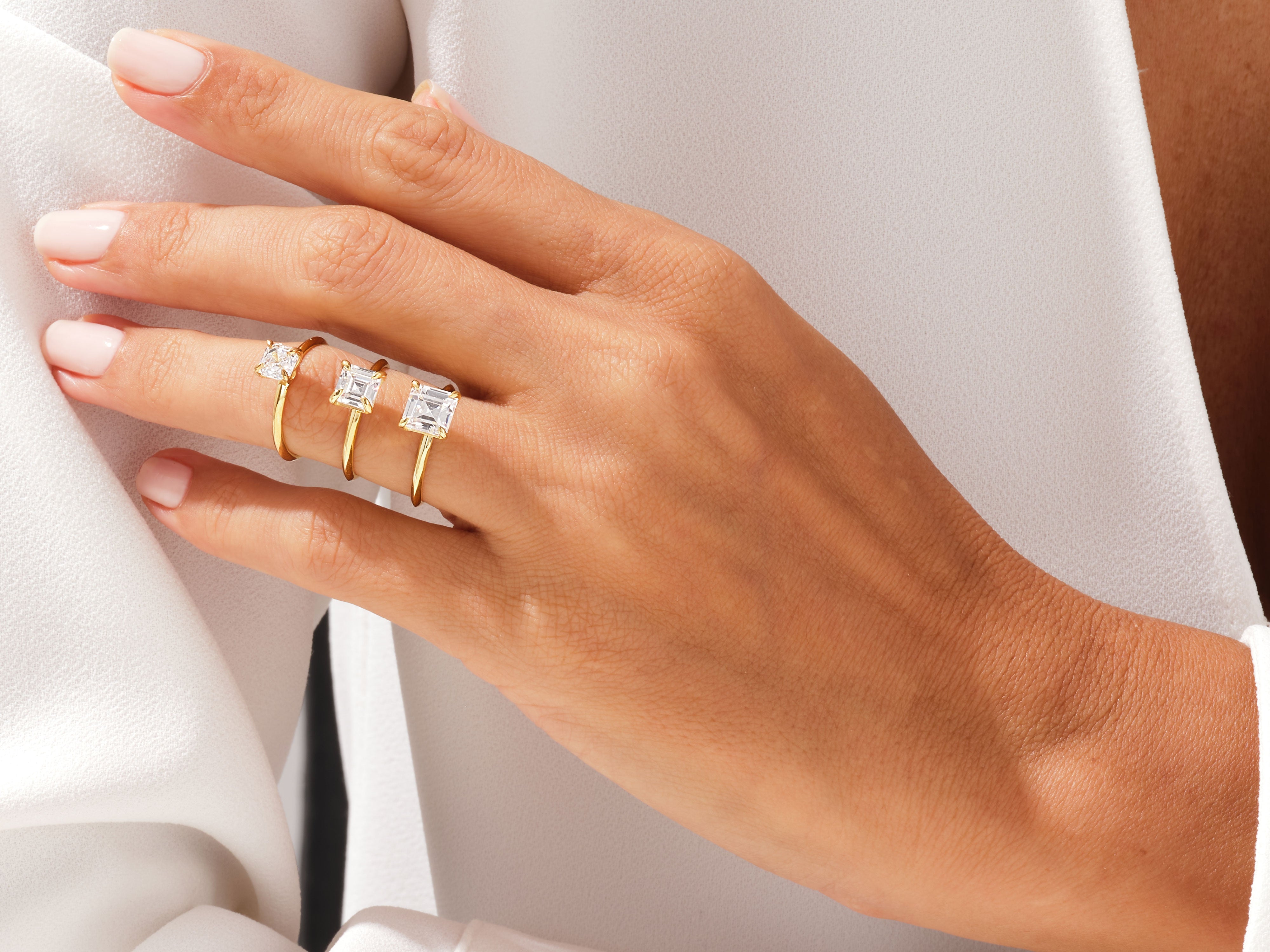 Gold rings with princess cut diamonds on a hand