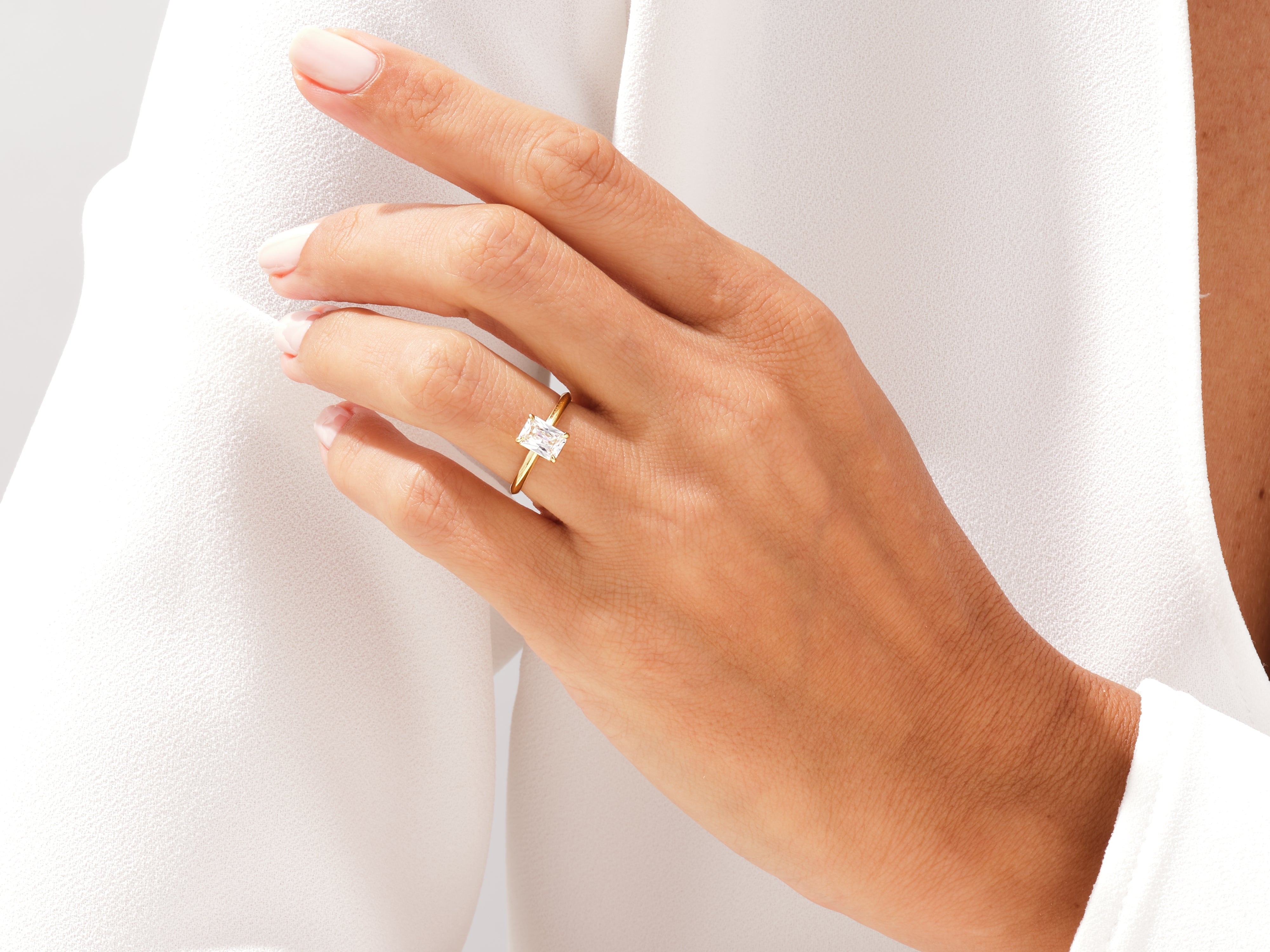 Gold ring with emerald-cut diamond on a woman's finger