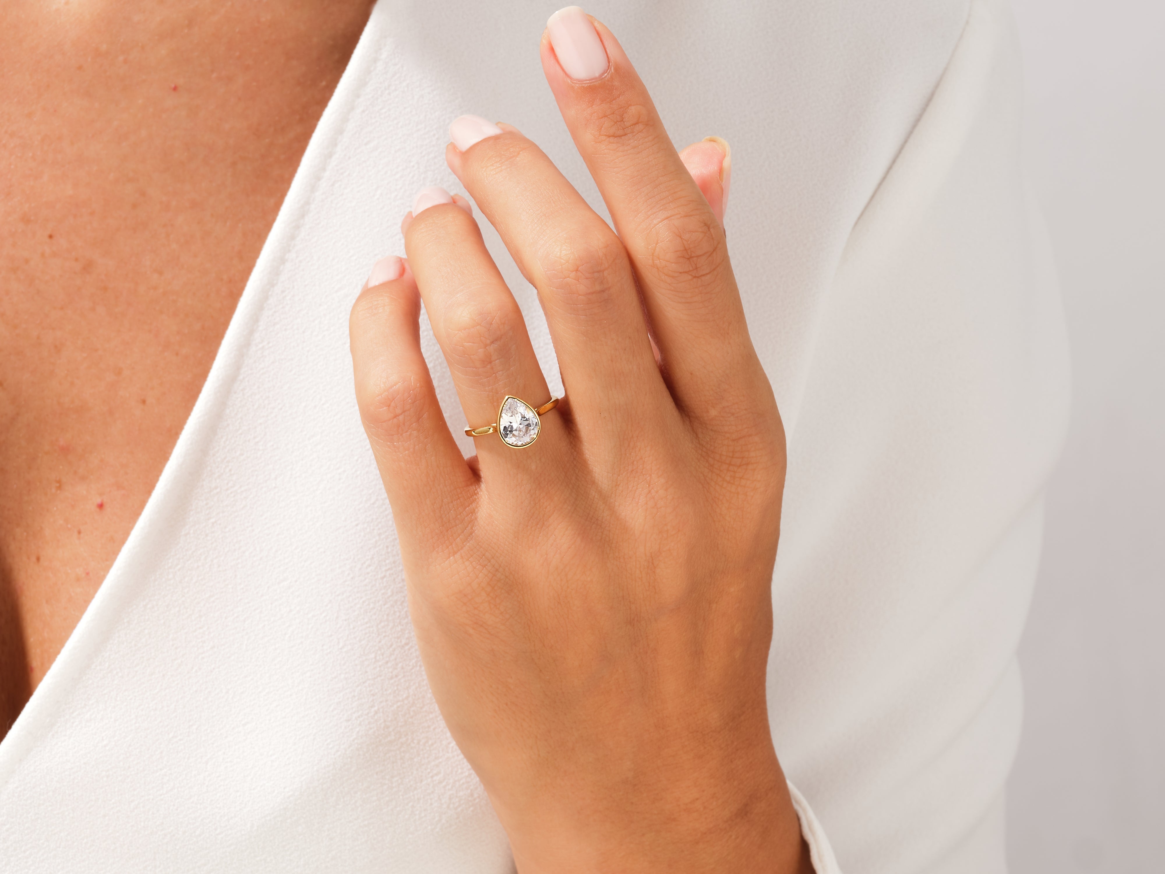 Gold pear-cut diamond engagement ring on a woman's hand