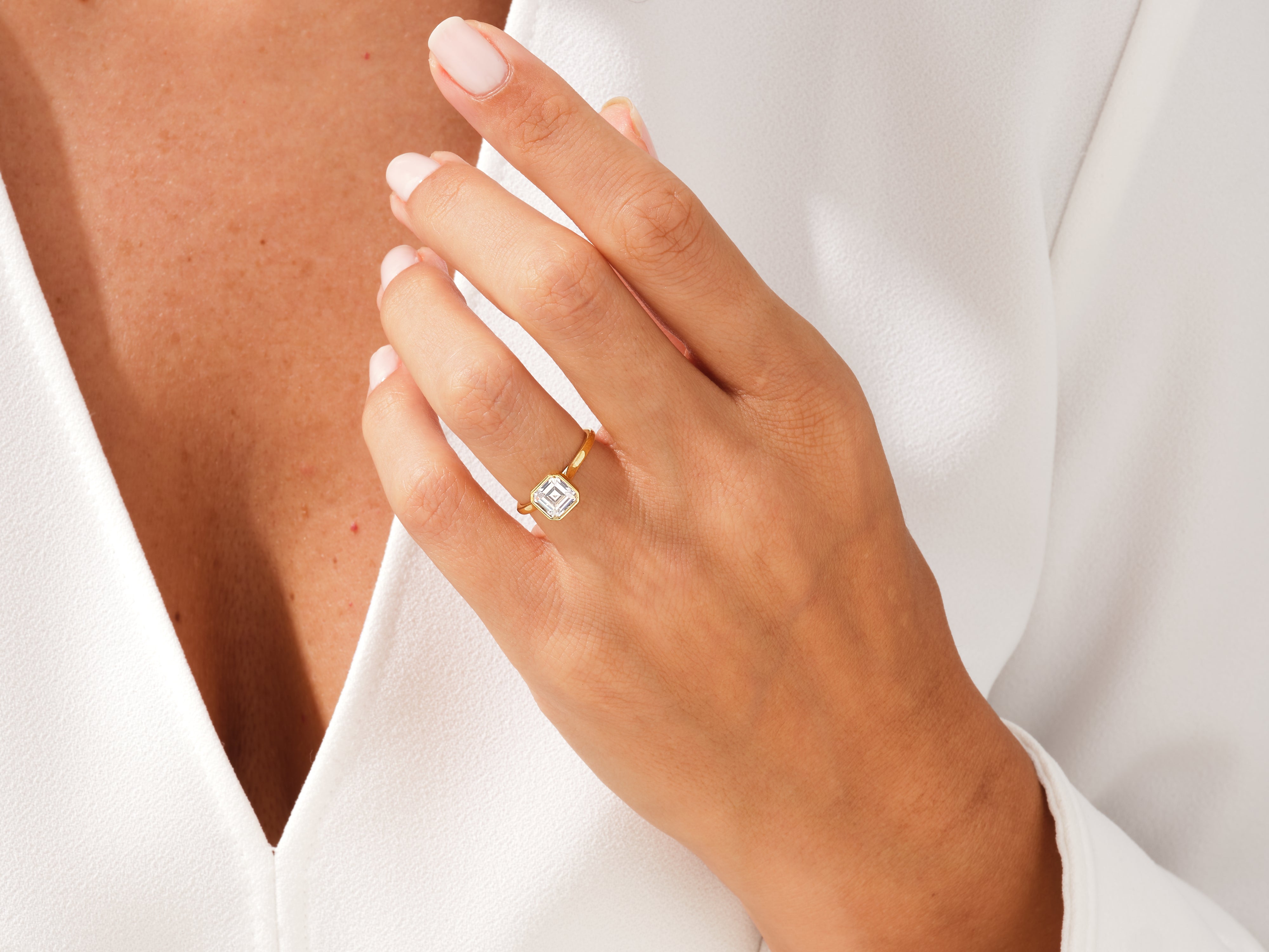 Gold ring with emerald cut diamond on a woman's hand