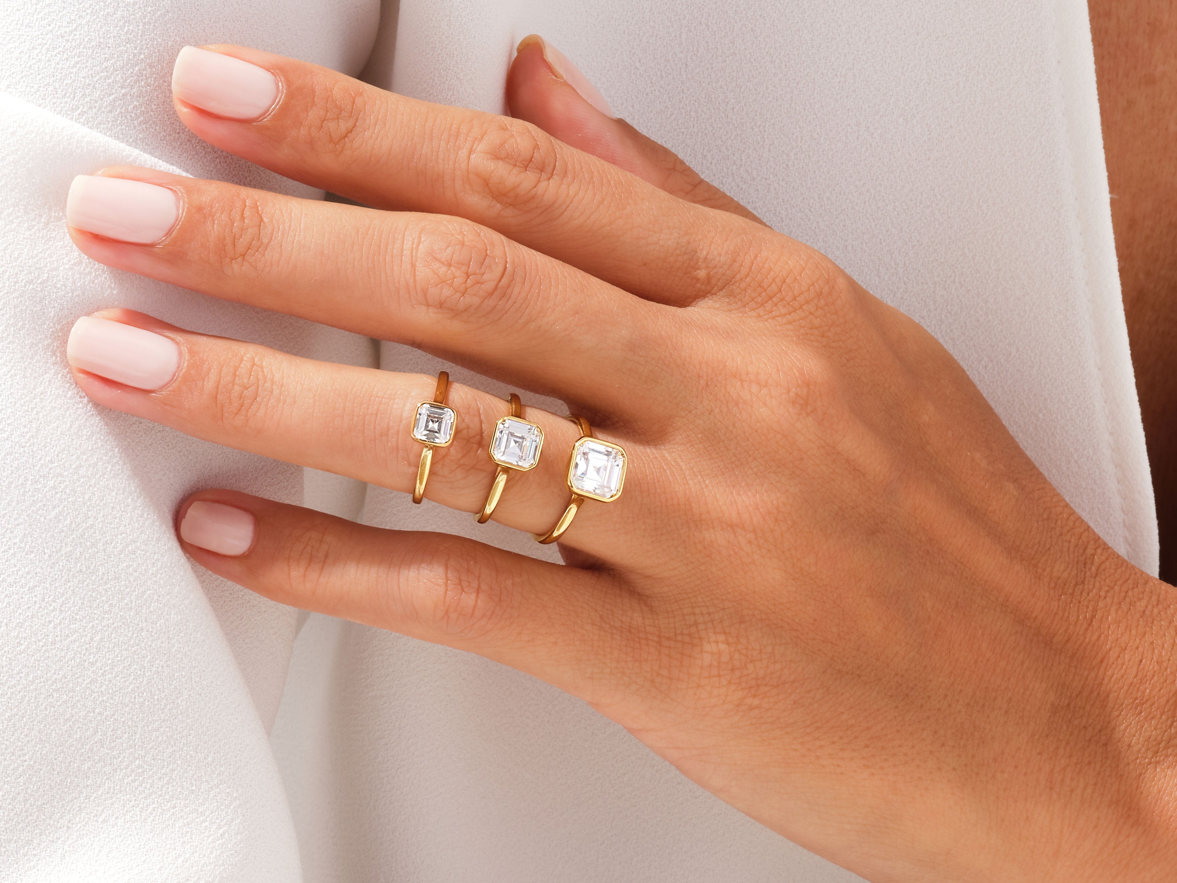 Gold rings with emerald-cut diamonds on a hand
