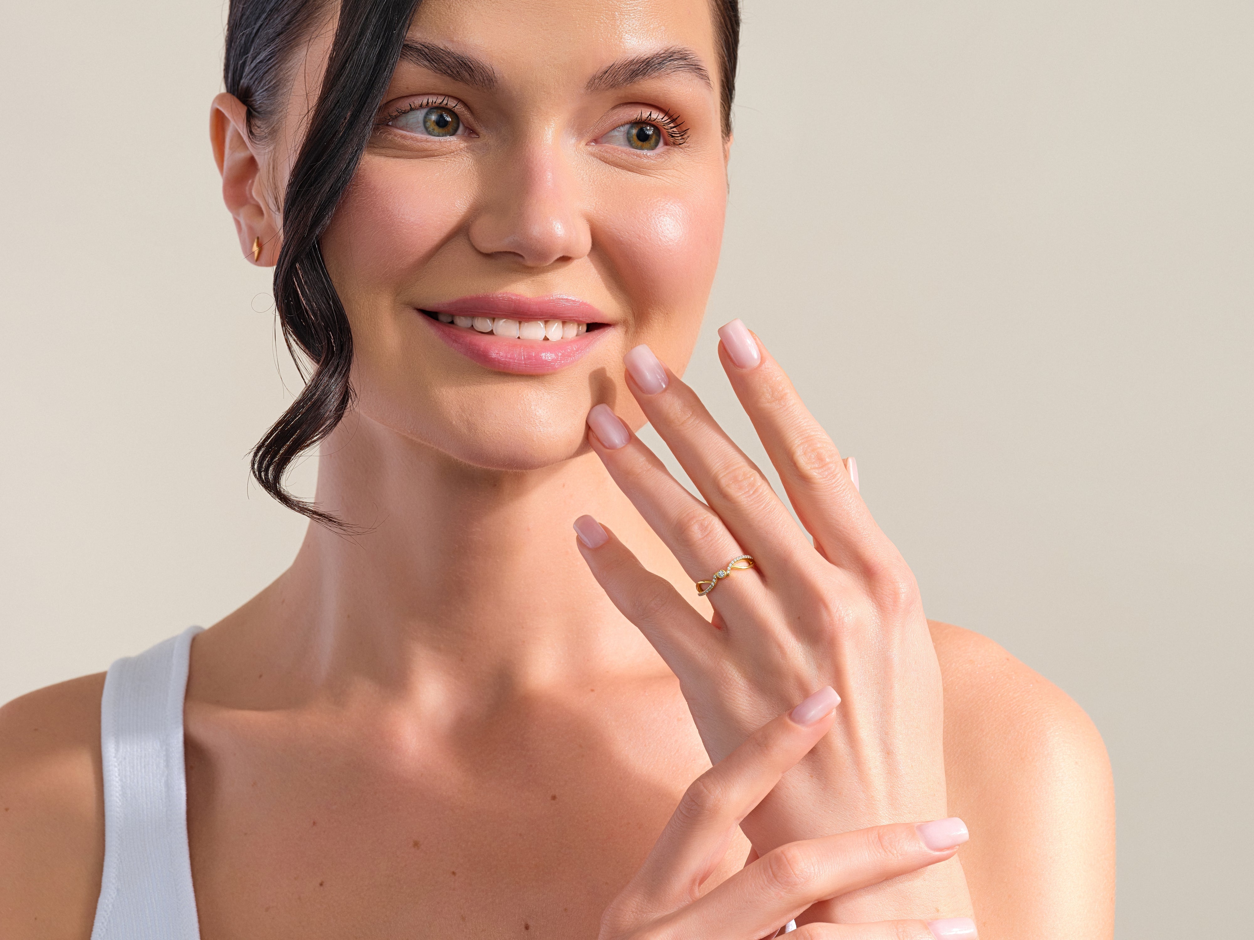 Woman wearing a delicate gold diamond ring and stud earrings