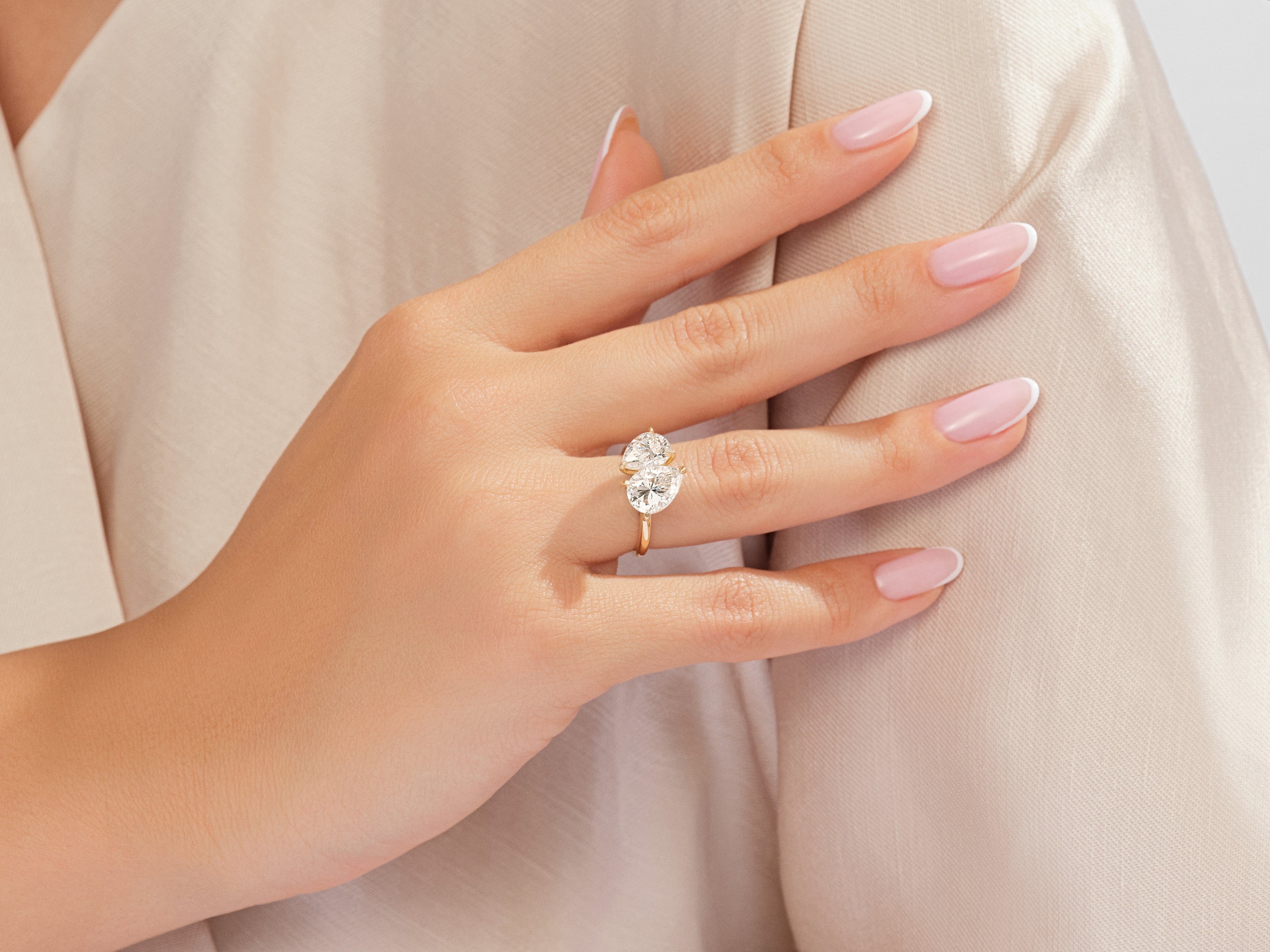 Diamond engagement ring with two pear-shaped stones on a hand