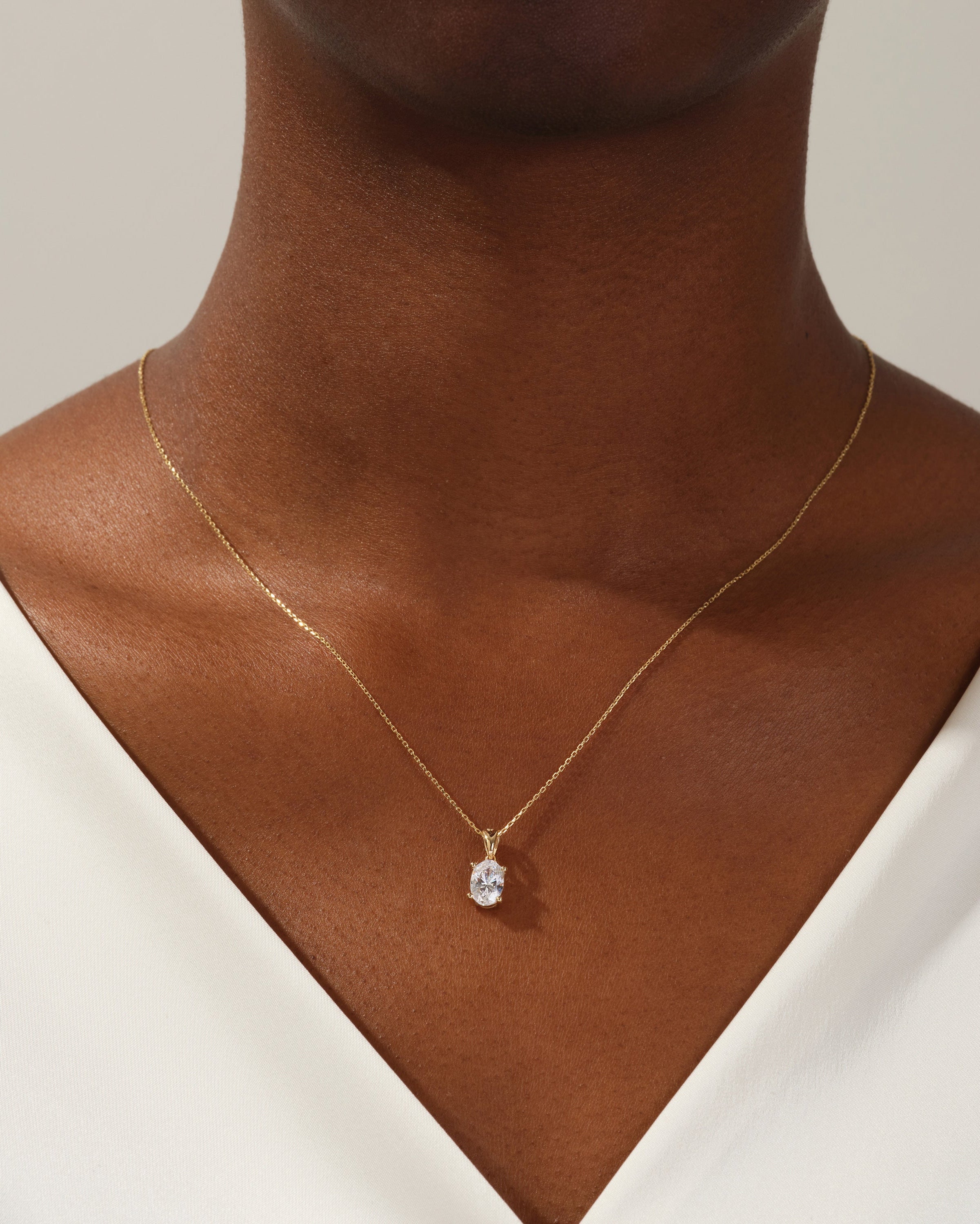 Gold necklace with oval diamond pendant on model