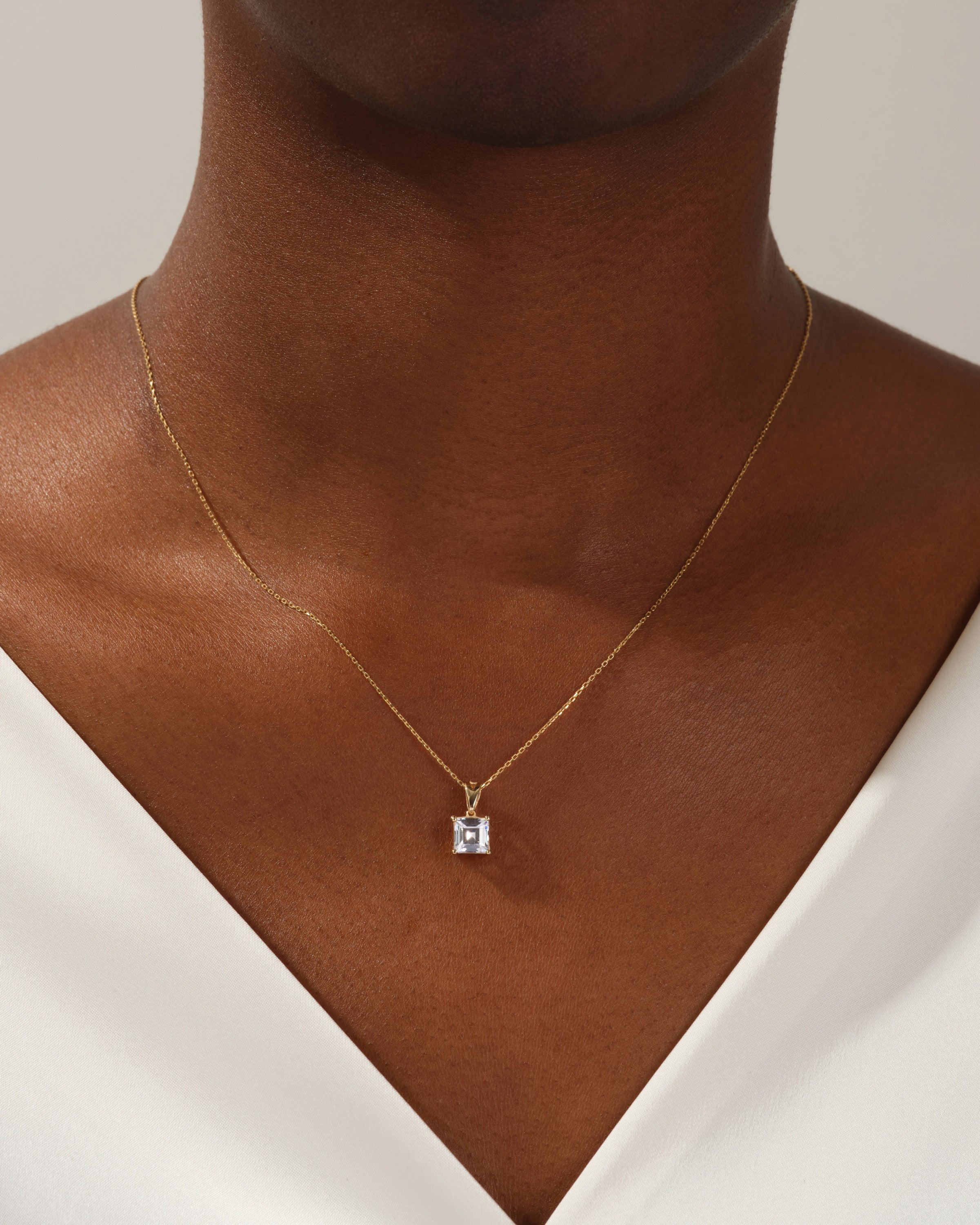 Gold necklace with emerald-cut diamond pendant on a woman's neck
