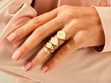 Gold signet rings with engraved initials on a hand