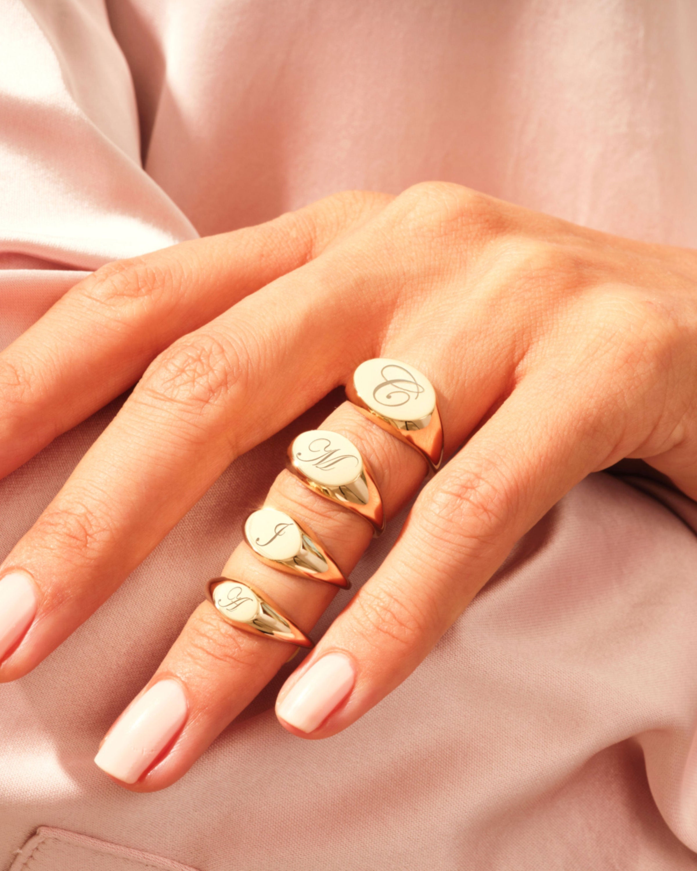 Gold initial signet rings on a hand, jewelry