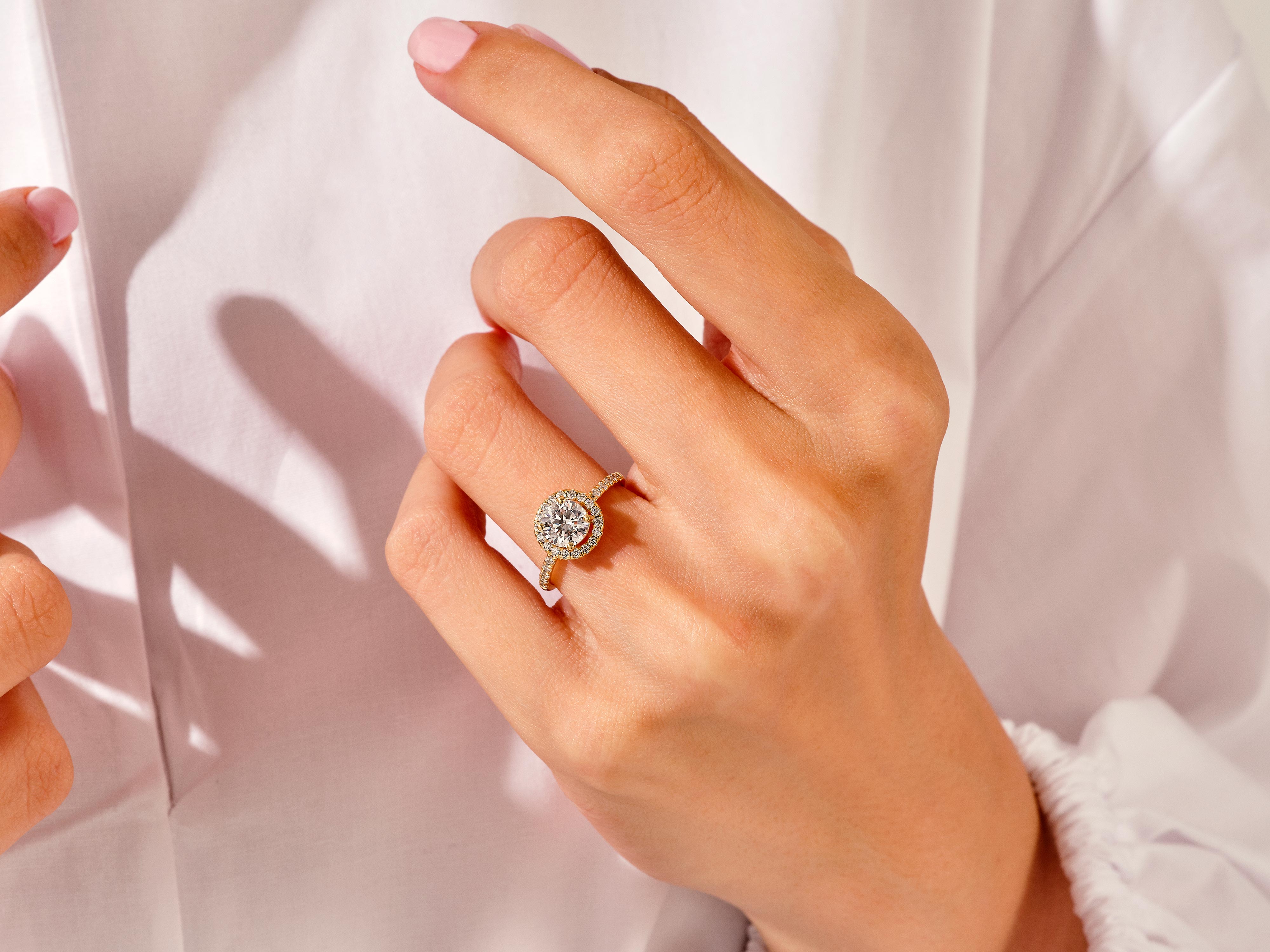 Diamond halo engagement ring on a hand