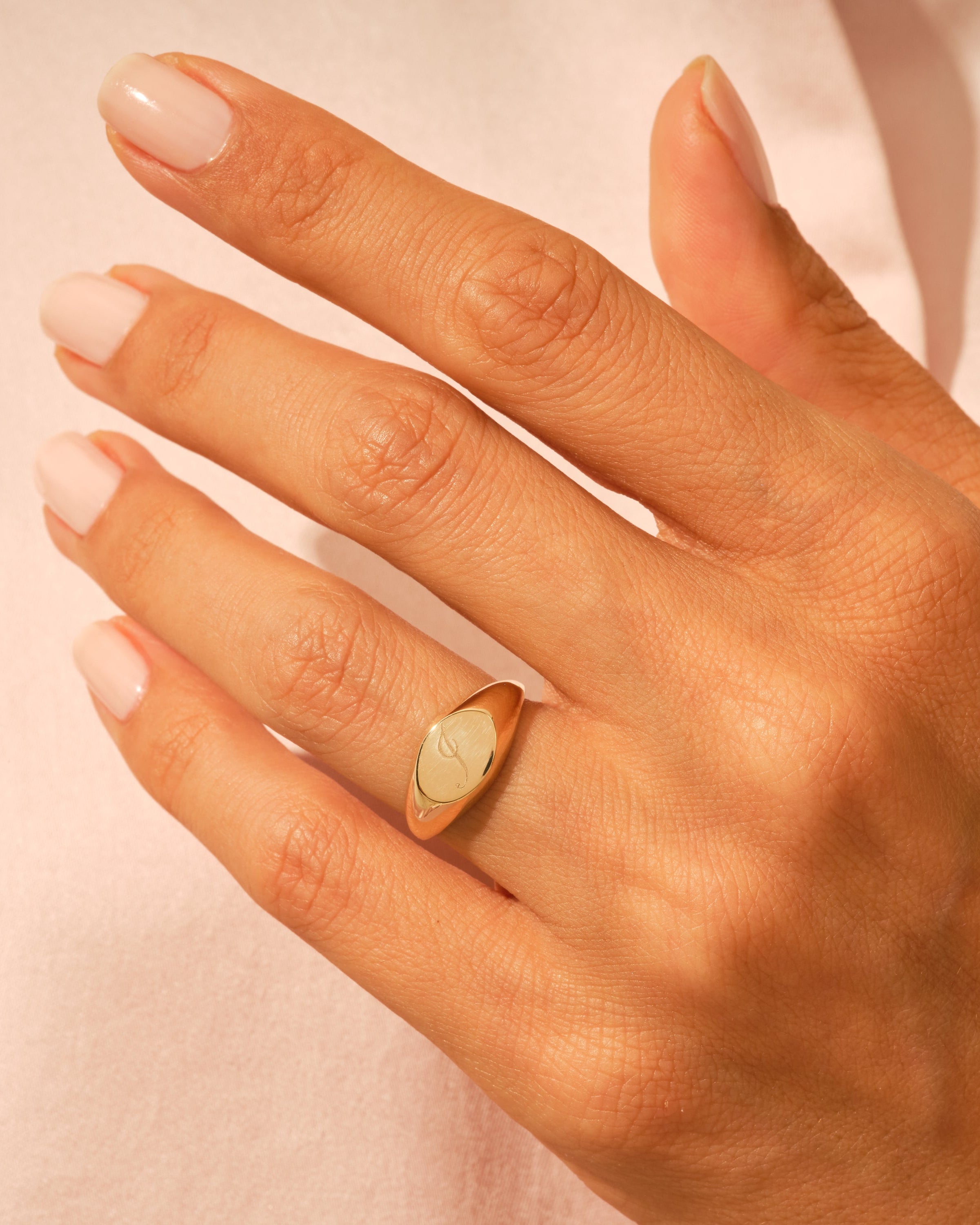 Gold signet ring with engraved initial on a woman's hand