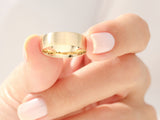 Gold brushed wedding band held by manicured hand
